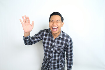 Fototapeta premium asian man laughing ecstatic with raising hand reaching forward wearing casual plaid shirt isolated on white background