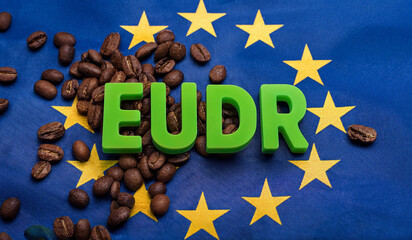 
EUDR word on roasted coffee beans and EU flag background. Concept for EU Deforestation or EUDR, regulation environmental policy and drinking coffee in European Union.