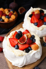 Pavlova cake (meringue dessert) with whipped cream, fresh berries and fig on table, closeup