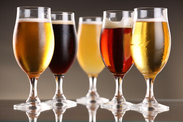 Glasses with different types of beer on mirror surface, closeup