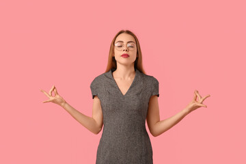 Beautiful young businesswoman meditating on pink background. Zen concept
