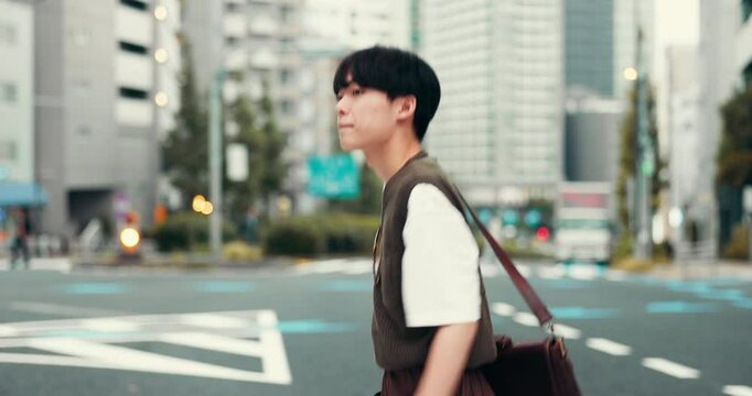 Asian man, student and walking in city for travel, morning commute and street crossing in Japan. Japanese person, pedestrian or bag in Tokyo with buildings, eco conscious or rushing to class schedule