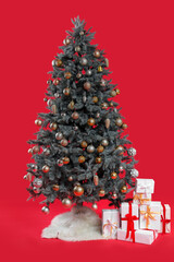 Different presents under beautiful Christmas tree on red background