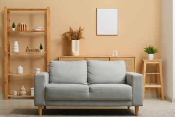 Modern interior of living room with grey cozy sofa and shelving unit