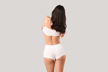 Pretty young woman in underwear on light background, back view