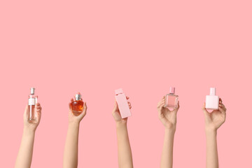 Female hands with many bottles of perfume on pink background