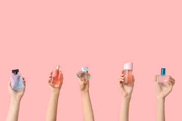 Fototapeta premium Female hands with many bottles of perfume on pink background