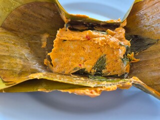 Traditional steamed fish with red curry paste wrapped in banana leaf. Famous ancient street food menu concept.
