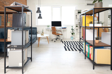 Interior of modern office with workplace, shelf units and plants