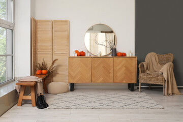 Interior of hallway with autumn decor, commode and armchair