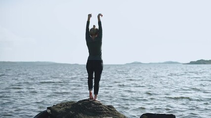 A middle-aged woman practices yoga qigong by the seaб person on the edge of the sea. - Powered by Adobe