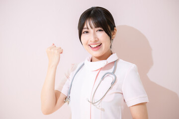 ガッツポーズをする背景ピンクの看護師のクローズアップ　カメラ目線