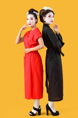 Beautiful young geishas on yellow background