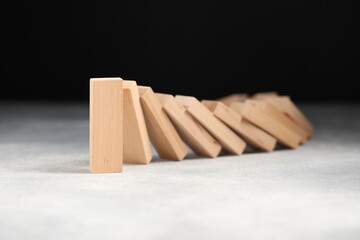 Domino effect. Wooden blocks falling on grey table, closeup