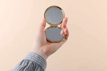 Woman holding pocket mirror on beige background, closeup © New Africa