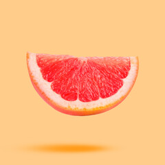 Sliced fresh juicy grapefruit in air on light orange background. Citrus fruit