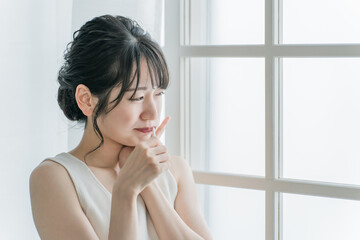 虫歯が痛い・しみて頬を押さえるアジア人女性
