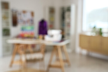 Blurred view of light atelier with tailor's workplace, shelf units and mannequin