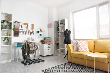 Interior of light atelier with tailor's workplace, sofa and mannequin