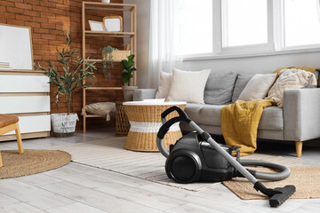 Modern vacuum cleaner on rugs in living room interior