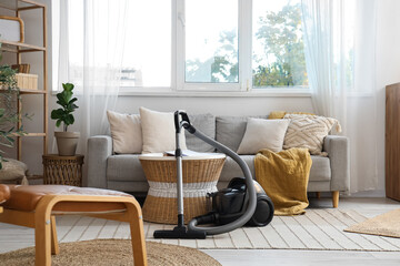 Interior of modern living room with vacuum cleaner, sofa and table
