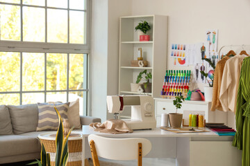 Tailor's workplace with sewing machine and fabric samples in atelier