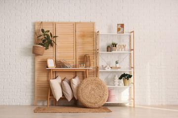 Interior of cozy room with wooden folding screen, table and shelf unit