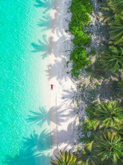 Aerial view beautiful topical beach with young man sunbathing relaxed in white sand  and coconut...