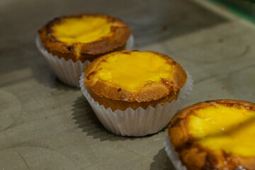 the irresistible allure of freshly baked egg tarts, their golden, flaky crusts perfectly crisp and their creamy custard filling gleaming under the light.