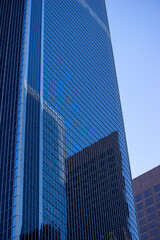 Obraz premium A close-up view of modern office buildings in downtown Los Angeles. The buildings feature sleek glass facades that reflect the surrounding structures, creating an intricate pattern of reflections.