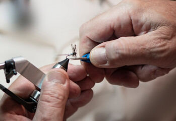 close up of hands tying a fishing fly