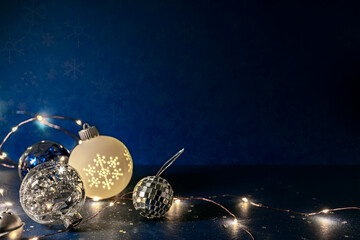 glass balls with glowing holiday garland lights. christmas decorations on dark blue background.