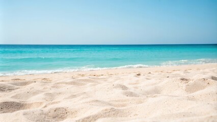 Fototapeta premium Serene coastal scene featuring soft, white sand and a tranquil turquoise ocean under a clear blue sky.