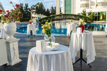 Pre-dinner cocktail tables by the pool at a summer resort hotel