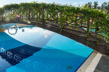 Wooden bridge decorated with green plants over the pool in a summer holiday hotel