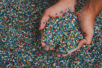 Hands hold clear white plastic pellets, raw materials for various manufacturing processes. These...