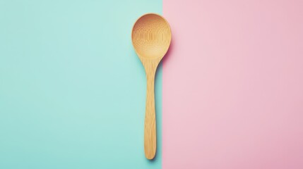 Wooden spoon on a pastel blue and pink background.