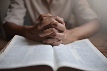 Naklejka premium close up of hands of unrecognizable black woman reading the Bible and praying.