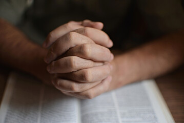 close up on the hands of an unrecognizable man reading the bible and praying. Concept of...