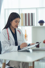 Focused Physician Reviewing Charts: A dedicated female doctor meticulously examines patient charts, showcasing professionalism and attentiveness in a clean, well-lit medical office.