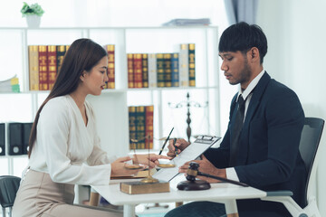 Legal Consultation:  A serious yet reassuring scene unfolds as a female client attentively reviews documents with her male lawyer in a modern, well-lit office.  The image conveys professionalism.