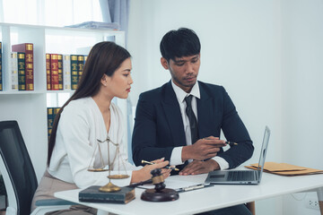 Legal Professionals Consulting:  A male and female lawyer collaborate intently on a case, reviewing documents and using a laptop in a modern, well-lit office setting.