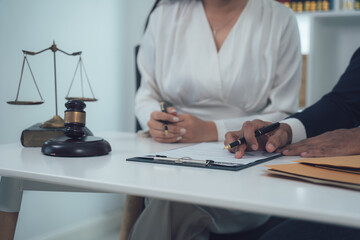 Legal Counsel Meeting:  Two lawyers, a man and a woman, review legal documents together at a desk.  The scene is professional and serious, with a gavel and scales of justice visible.