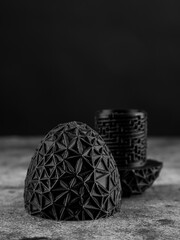 Close-up of a plastic egg model with ornament on a black background