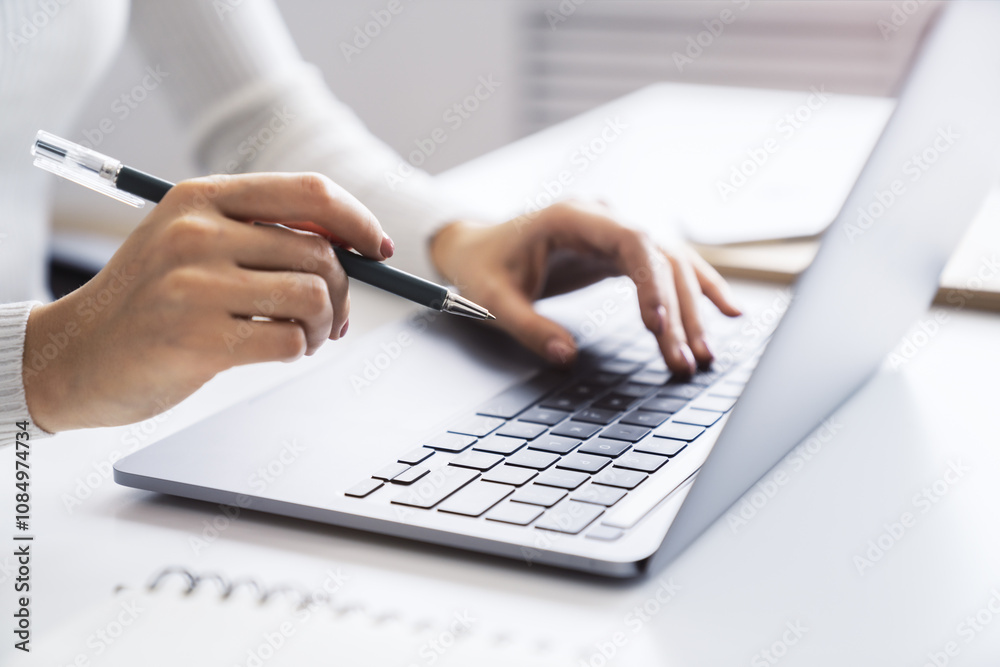 Poster a close view of a woman's hands typing on a modern laptop keyboard, office surroundings appearing fu