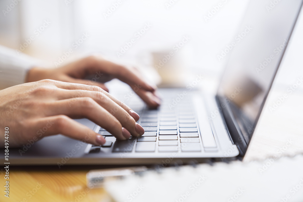 Poster the picture captures a woman's hands typing on a chic laptop keyboard, with a hazy office environmen