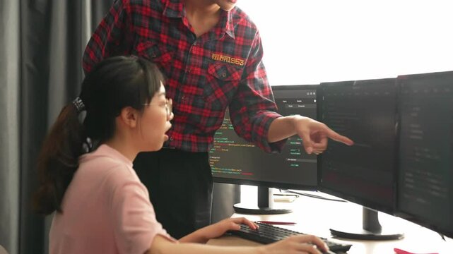 Back end or software developer manager supervising his team on new application program development on debugging and solving complex code algorithms on monitor. Burgeoning