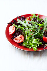 Salad with fresh tomatoes and arugula on a bright stone background. Close up. Copy space.