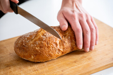 hands cut homemade rye bread on a wooden table