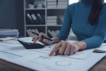 Focused Financial Analyst: A meticulous woman in a blue top is deeply engrossed in analyzing...